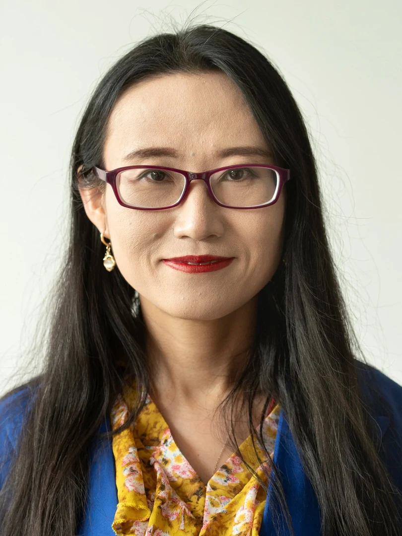 Eine Wissenschaftlerin und ein Wissenschaftler arbeiten hinter einer Glasfassade und mischen Chemikalien mit Großgeräten.