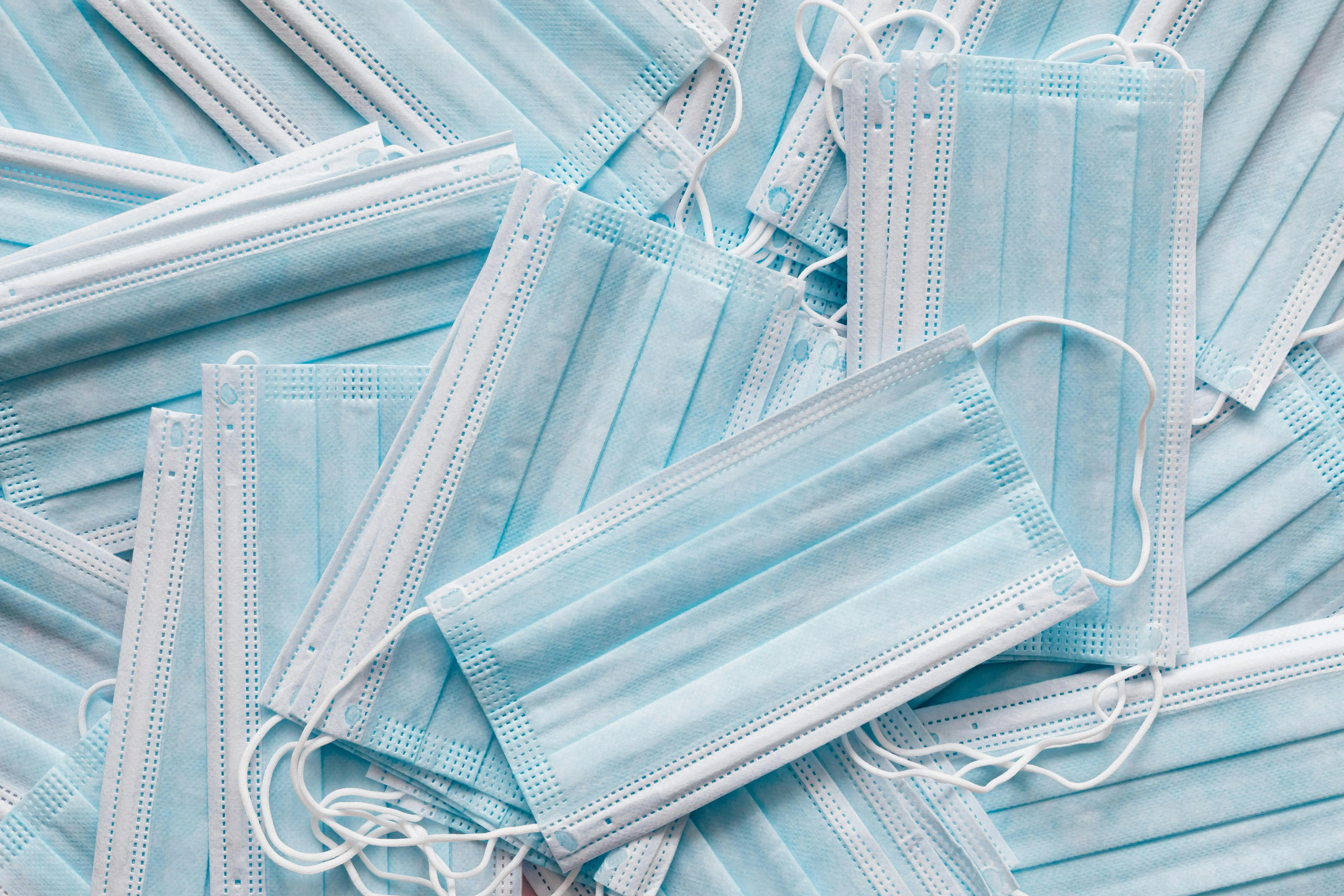 A pile of light blue medical face masks shot from above.