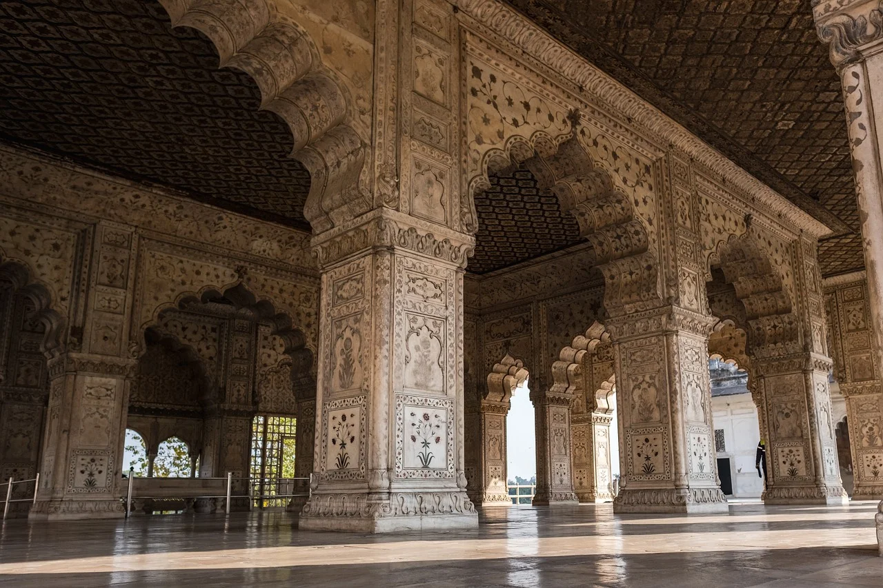 Historical building in India with columns and arches, decorated with detailed swirling patterns.